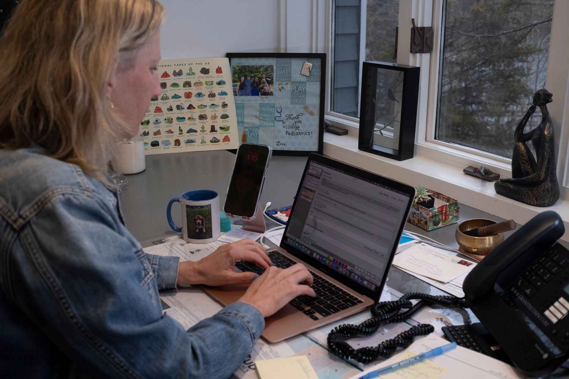 A woman is sitting at a desk typing on a laptop computer.