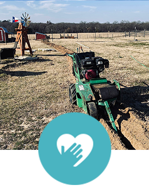A green tractor is digging a hole in a field.