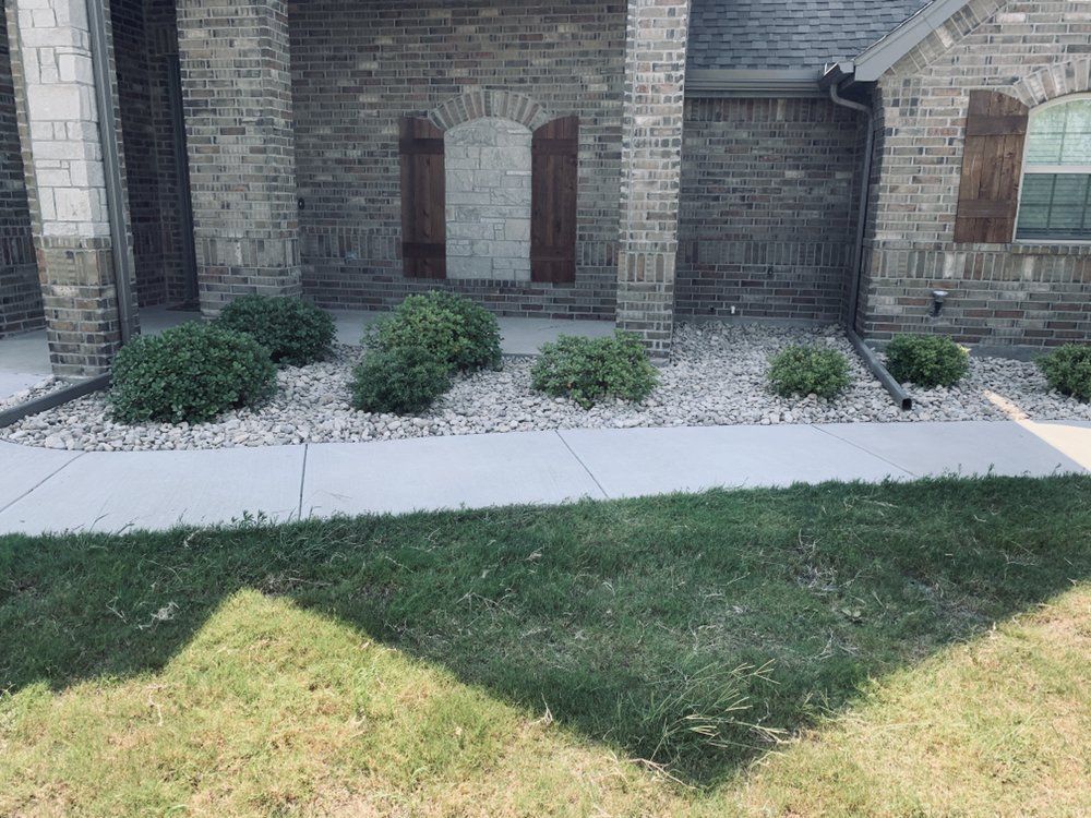 A brick house with a sidewalk and gravel in front of it.
