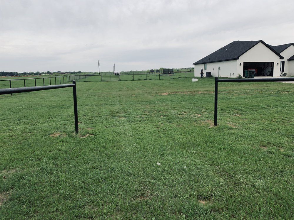 A large grassy field with a house in the background.