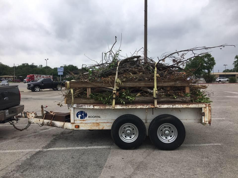 A trailer with a lot of branches on it is parked in a parking lot.