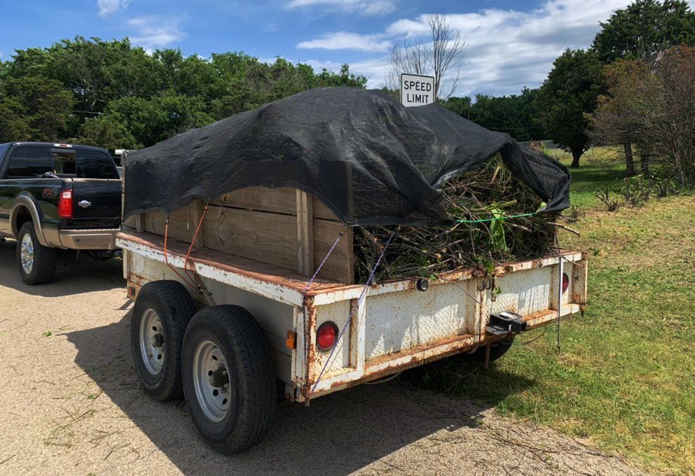 A trailer with a black tarp on top of it is parked next to a truck.