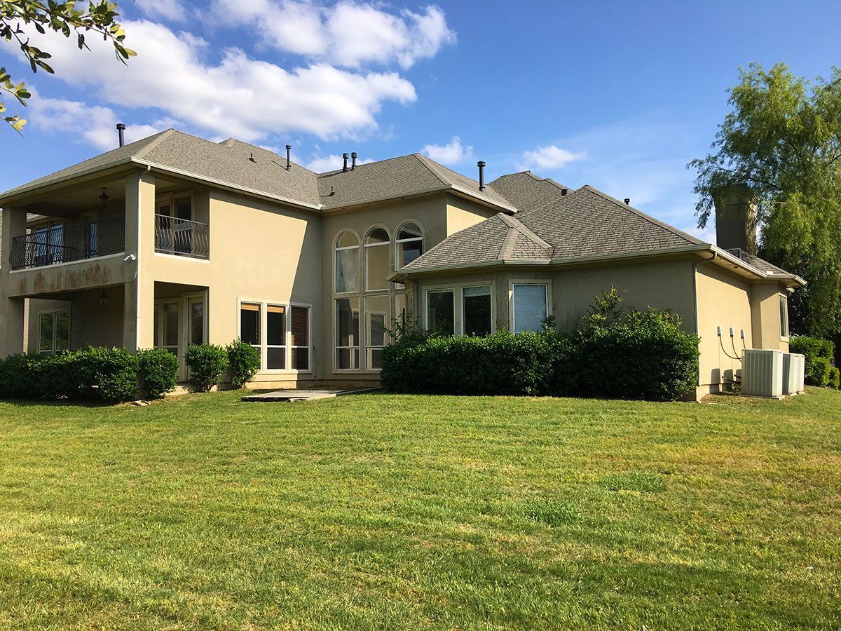 A large house is sitting on top of a lush green field.