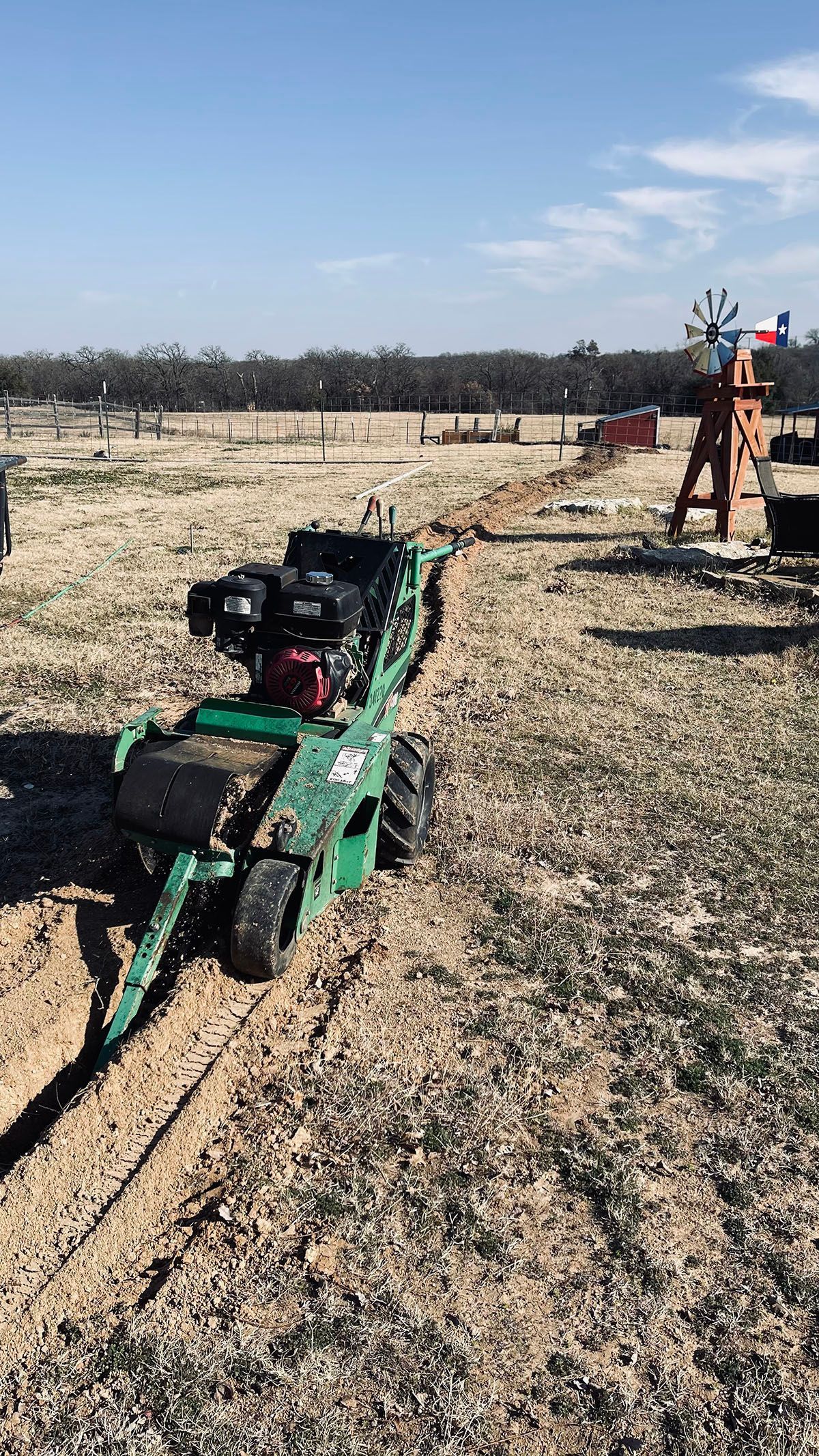 A green tractor is sitting in the middle of a field.