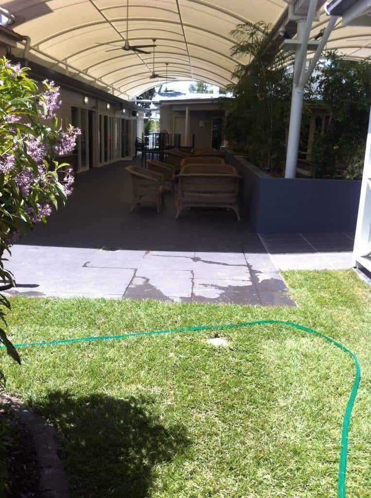 A Green Hose is Laying in the Grass in Front of a Building — Turf Central In Airlie Beach, QLD
