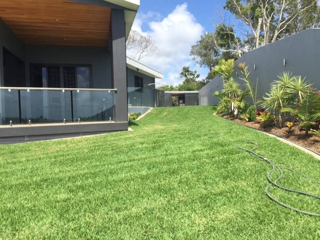 A Lush Green Lawn in Front of a House With a Hose — Turf Central In Chelona, QLD
