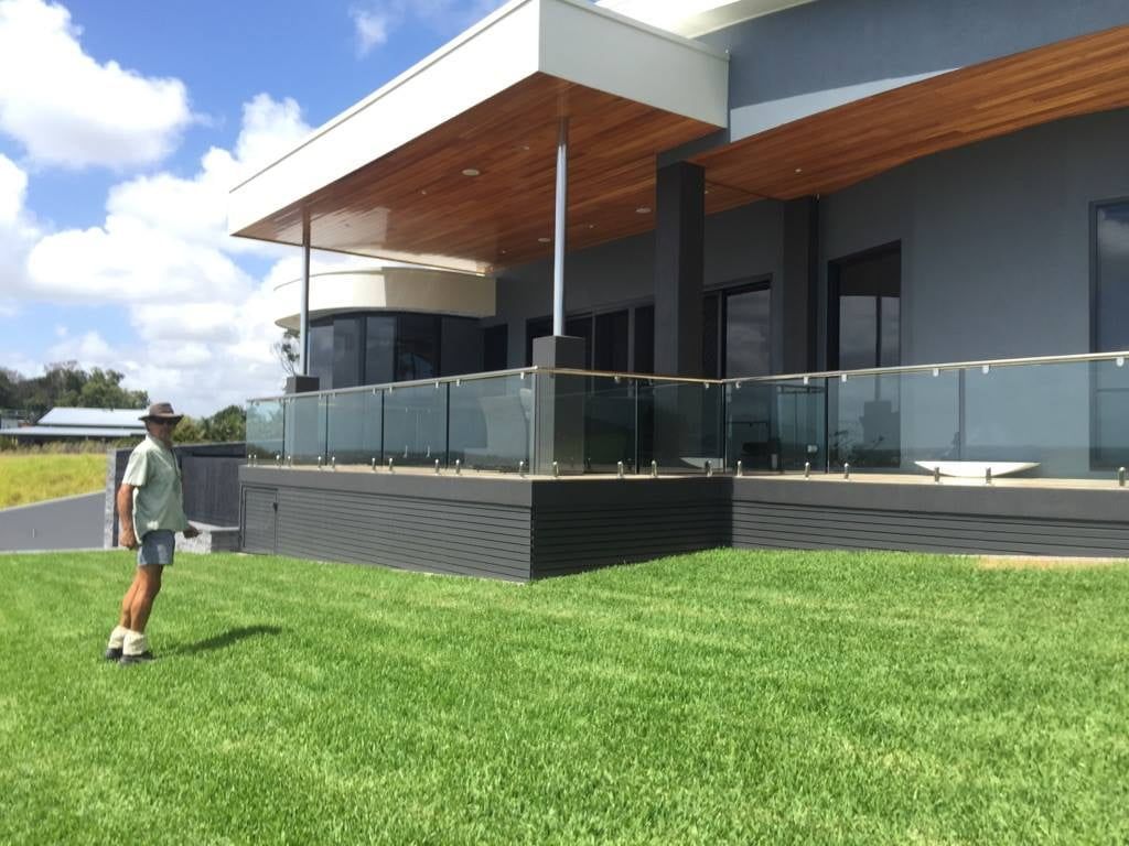 A Man is Standing in the Grass in Front of a House — Turf Central In Chelona, QLD
