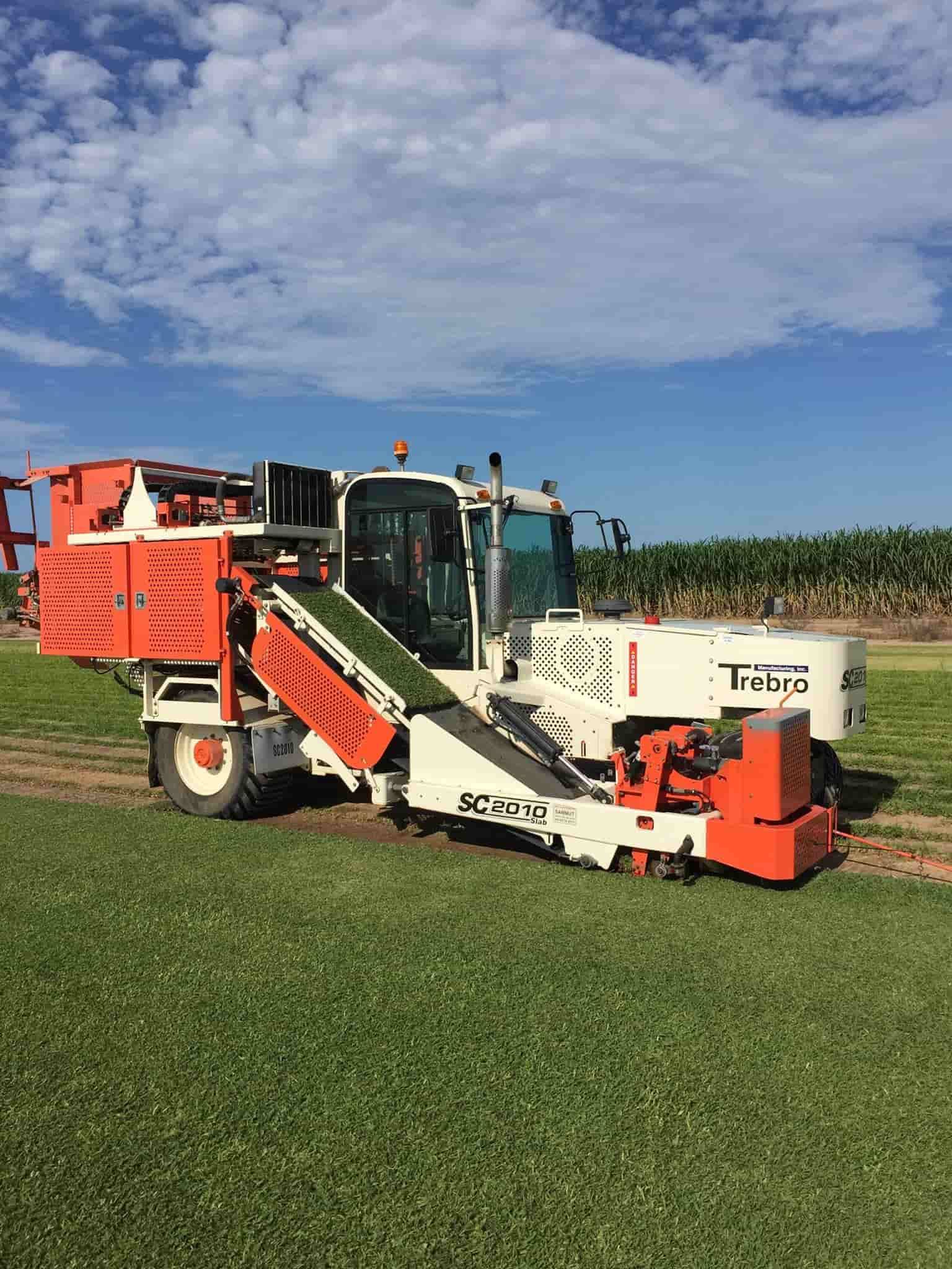 A Large Orange and White Machine is Sitting on Top of a Lush Green Field — Turf Central In Chelona, QLD