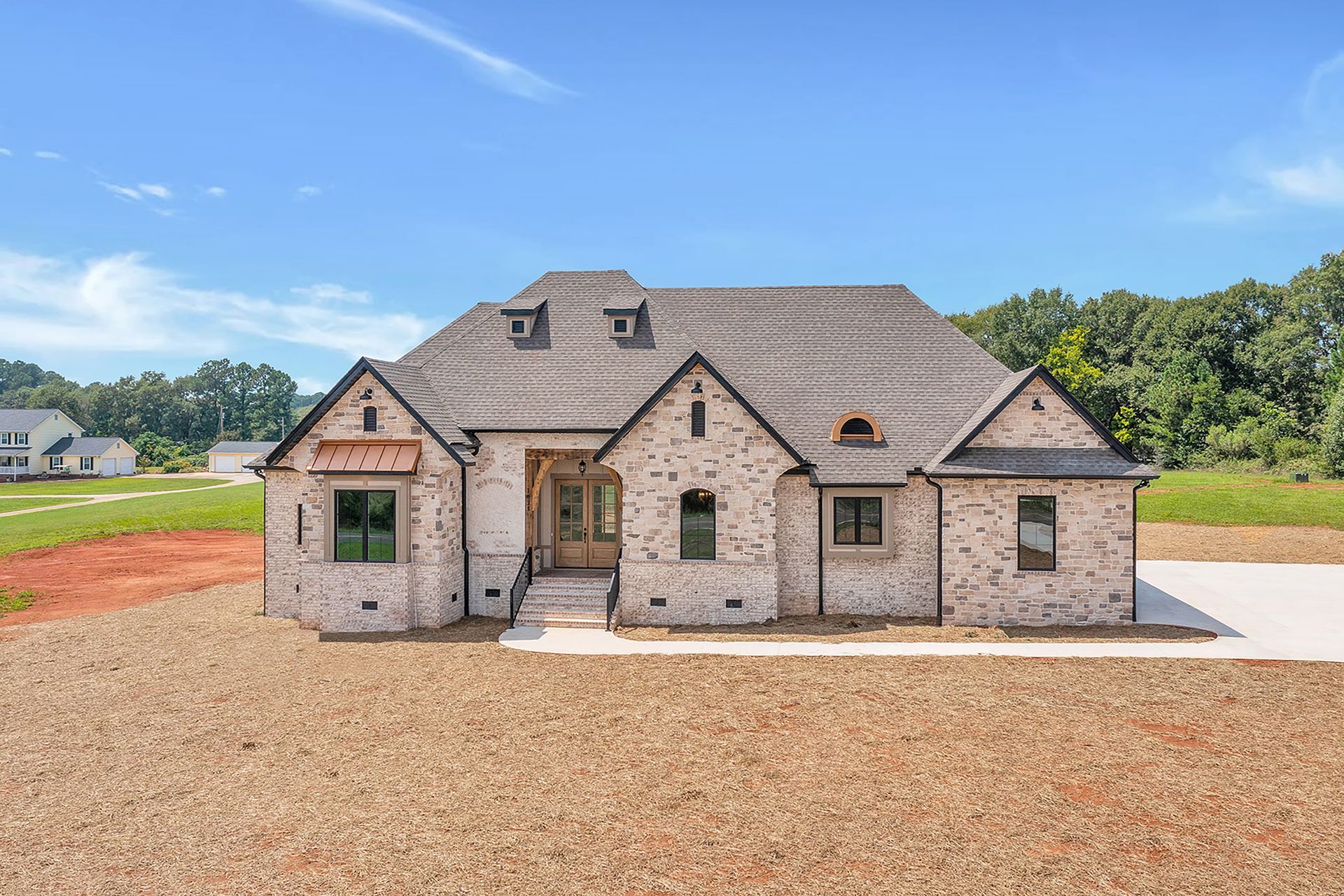 A large brick house is sitting on top of a dirt field.