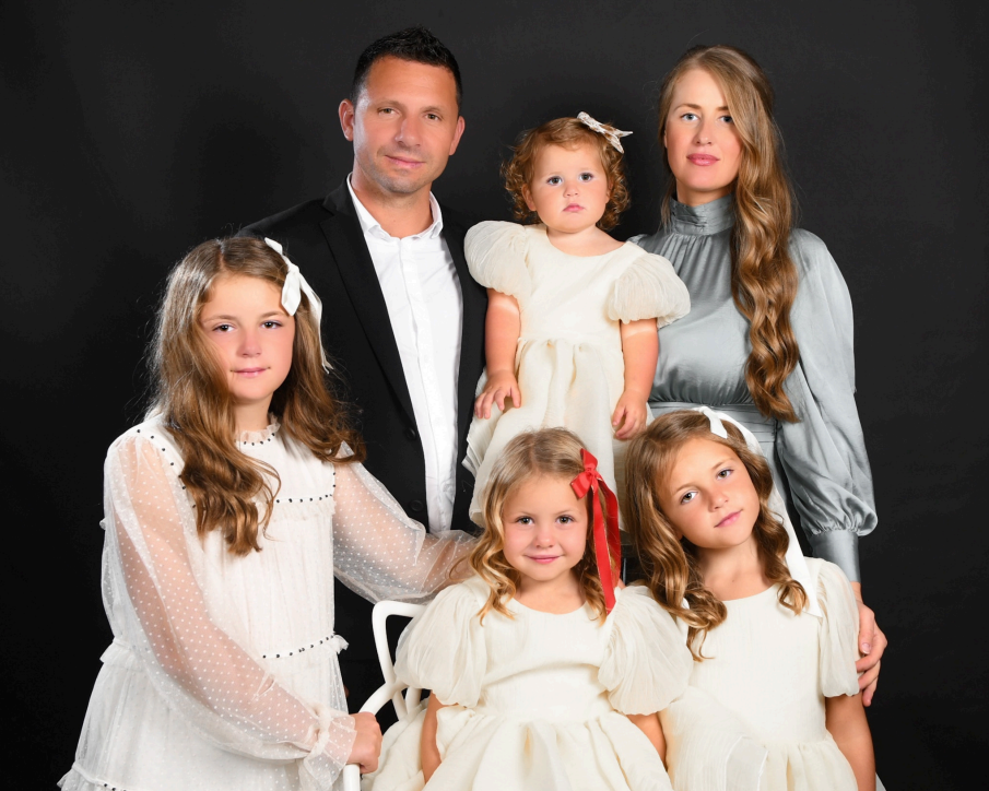 A family posing for a picture in front of a black background.