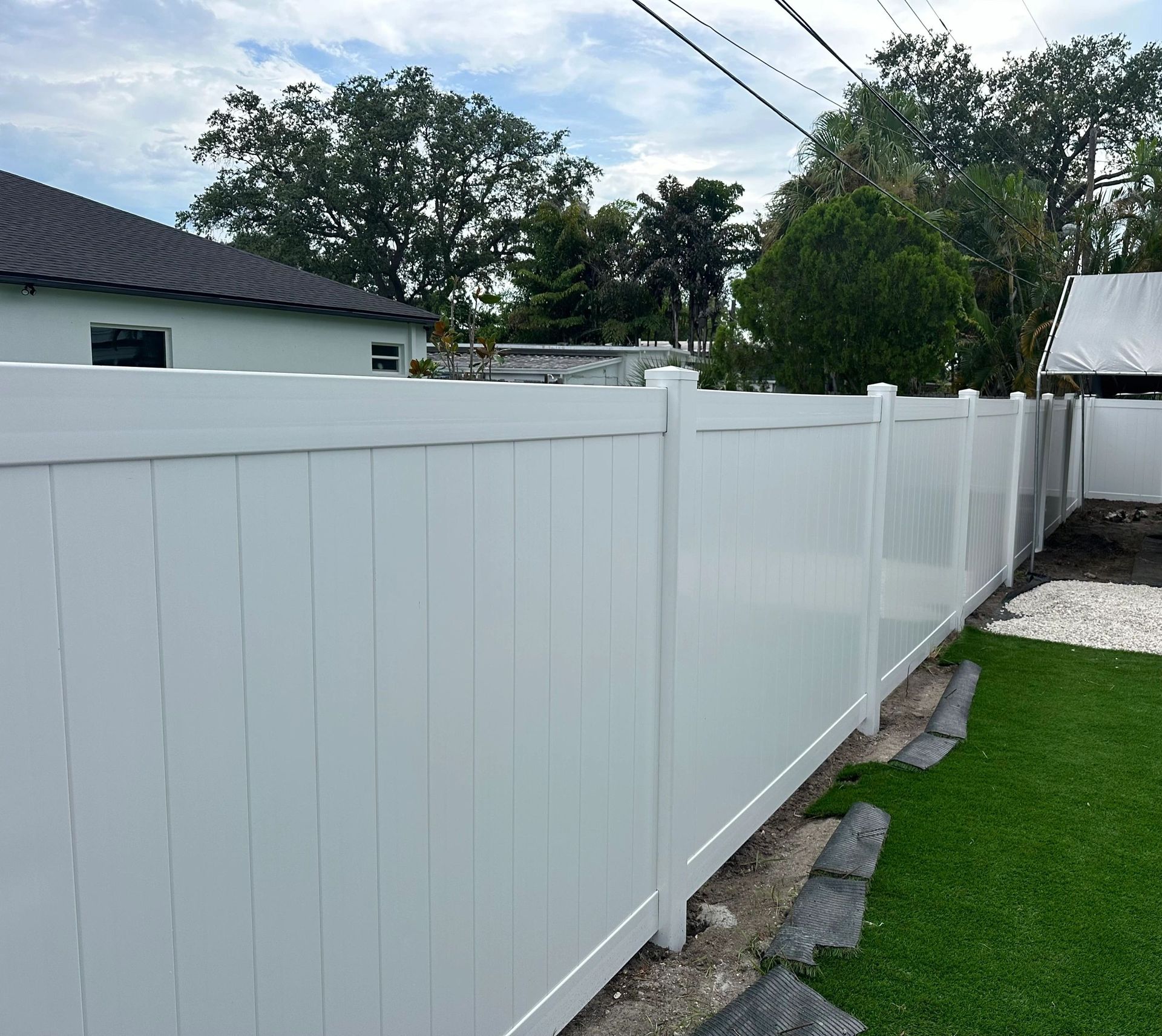 A white fence surrounds a grassy area in front of a house