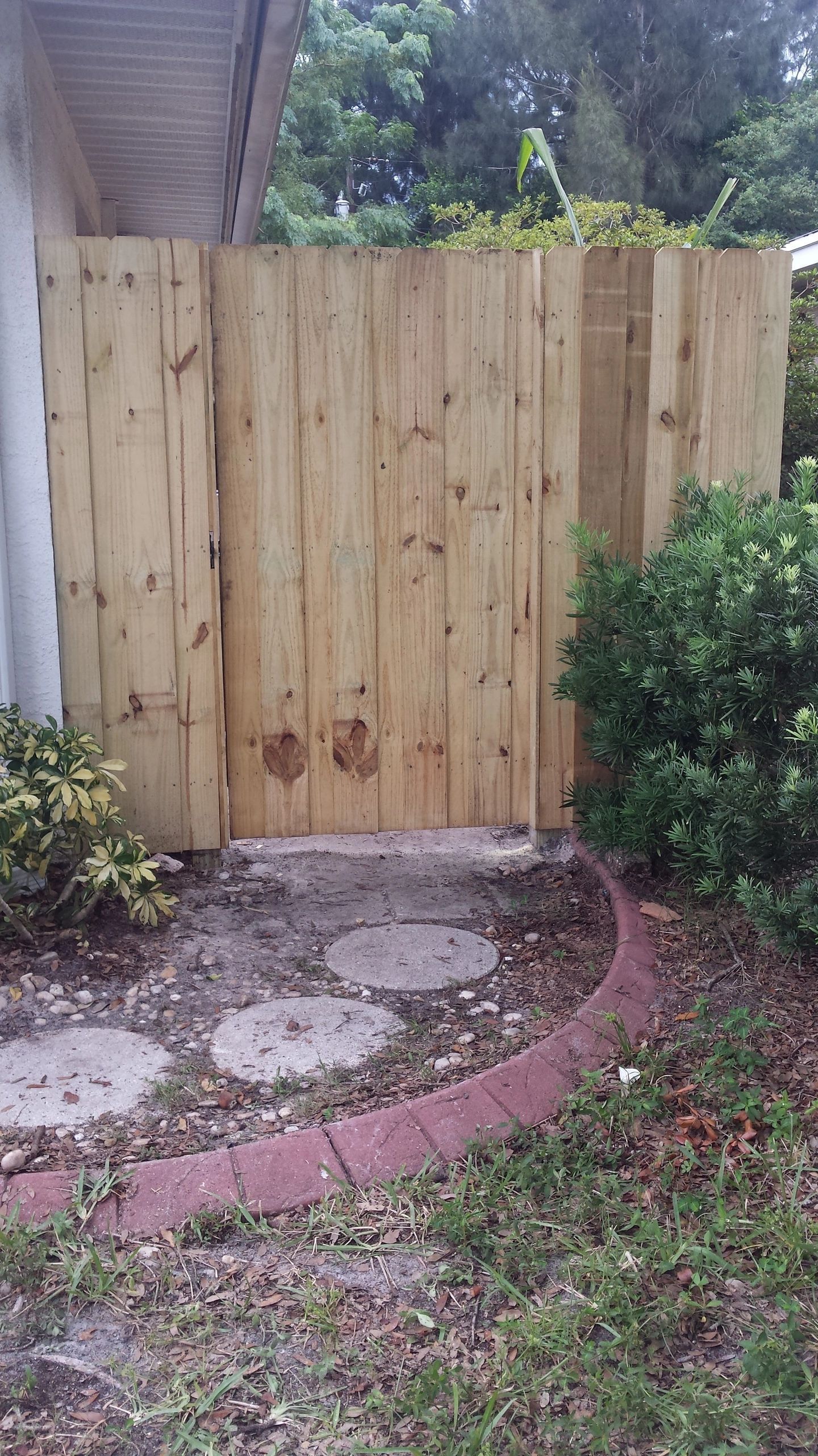 A wooden fence with a gate in the backyard of a house.