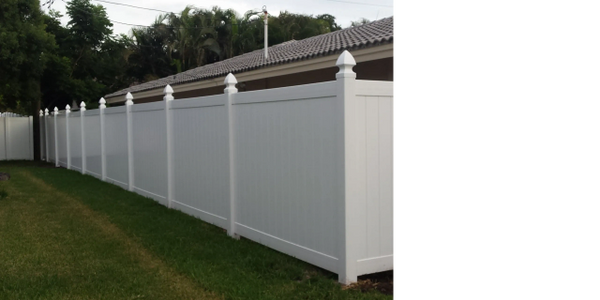 A white fence is sitting in the grass in front of a house.