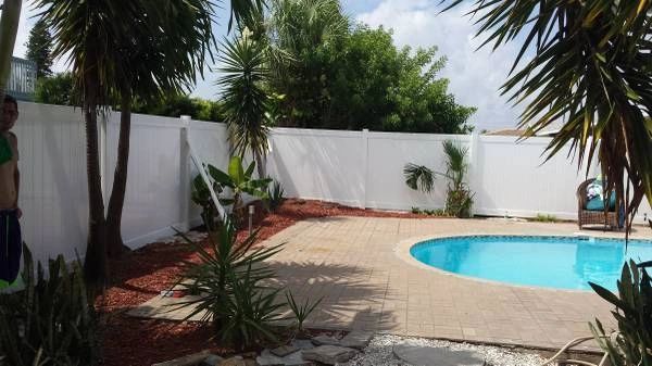 A man is standing next to a swimming pool in a backyard.