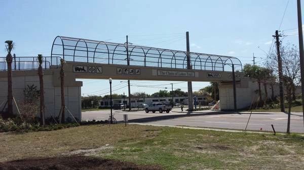 A bridge over a road with cars driving underneath it.