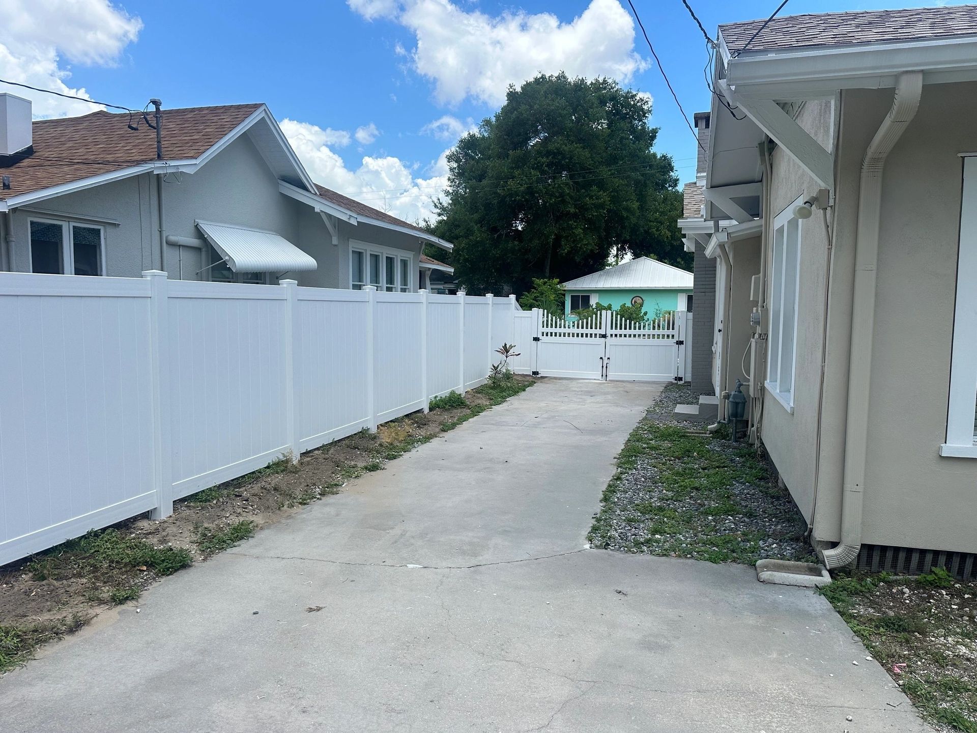 A driveway leading to a house with a white fence
