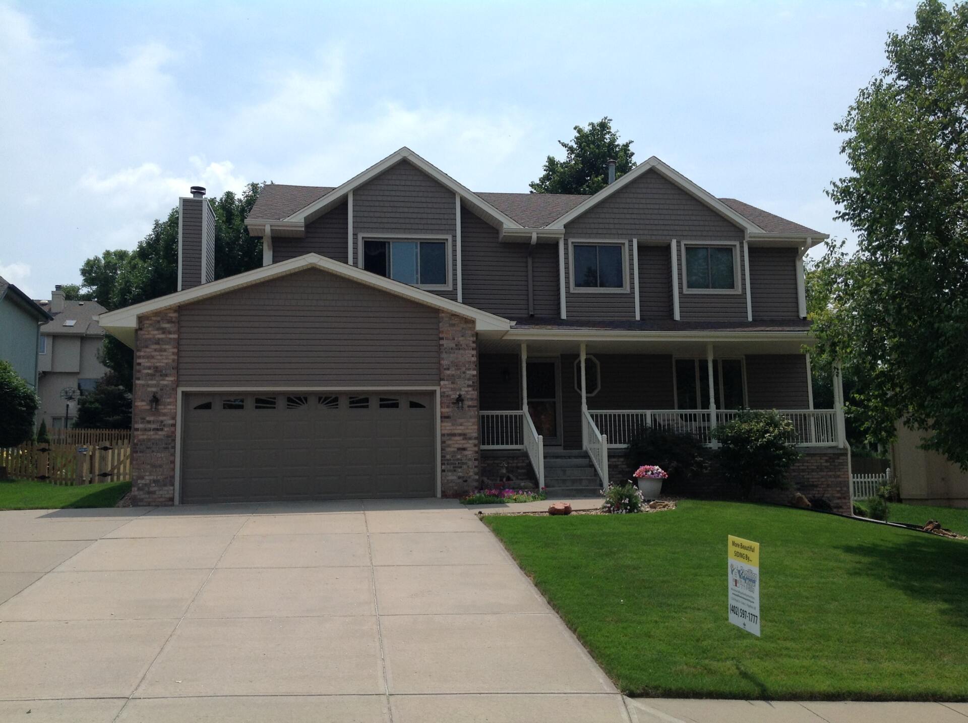 two story home with gray siding, porch, and front lawn