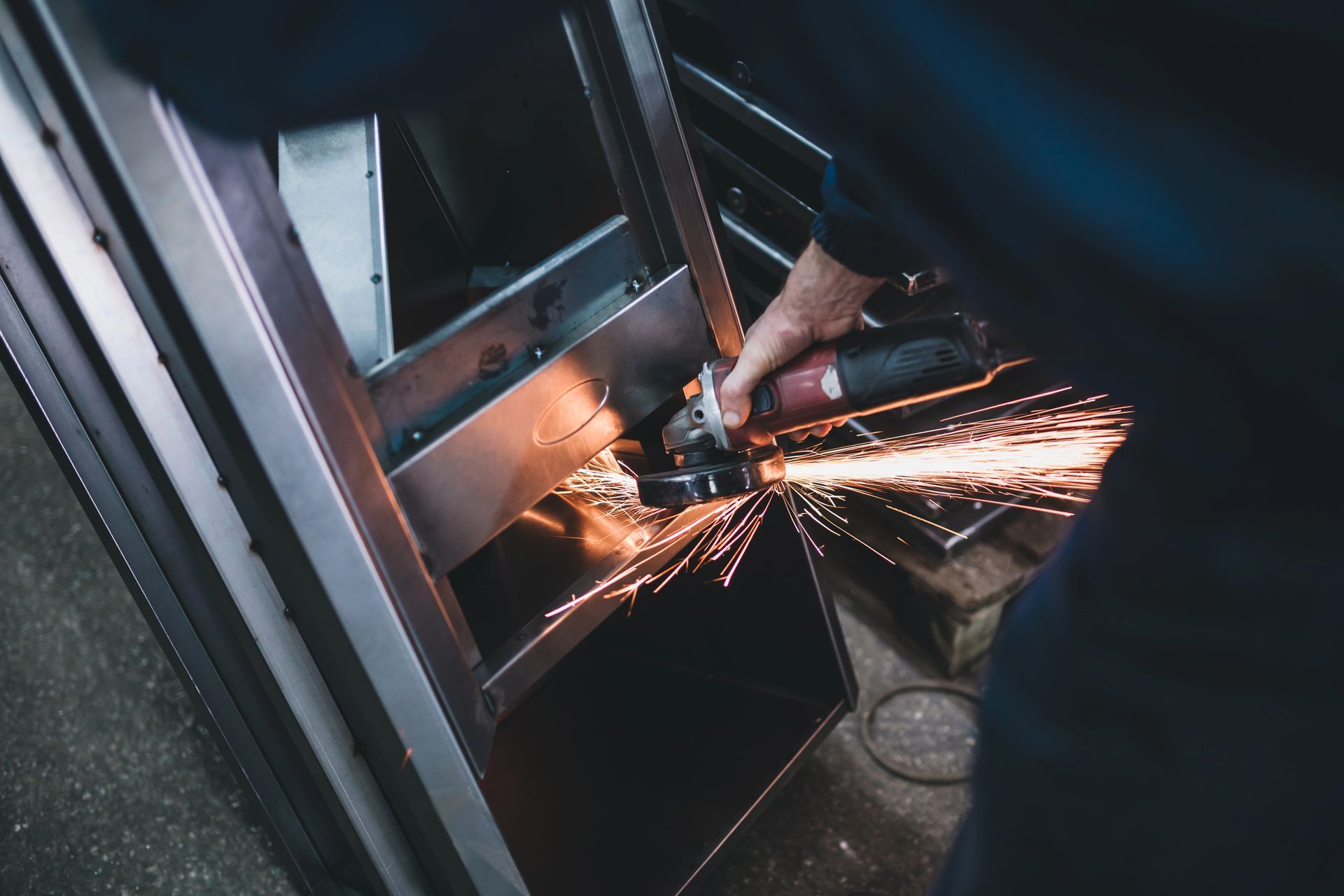 Una persona utiliza una amoladora sobre metal, creando chispas en un taller.