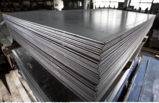 Pila de láminas de acero gris en un entorno industrial.