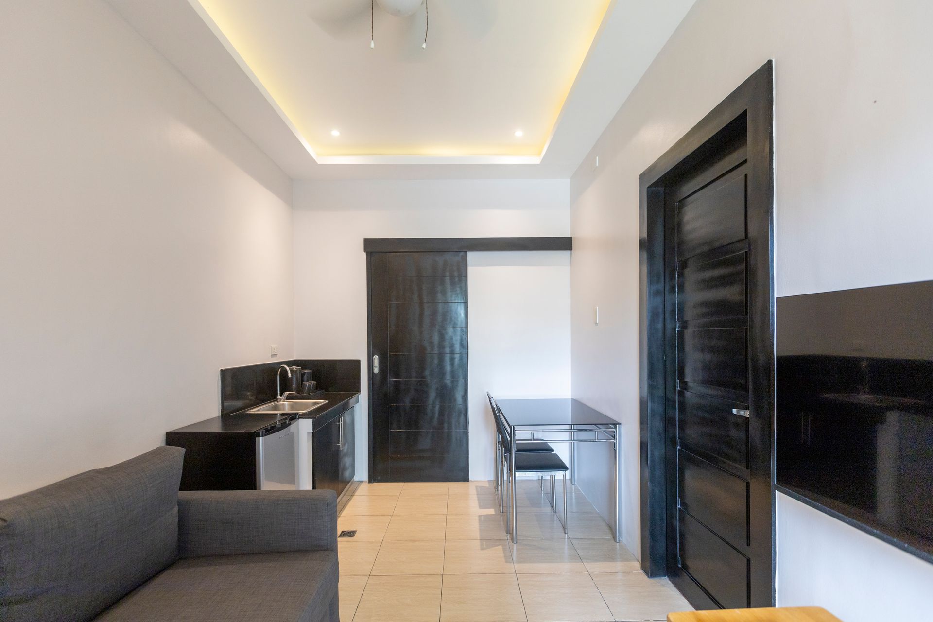 Interior view of a small apartment with a kitchenette, dining area, and sofa.