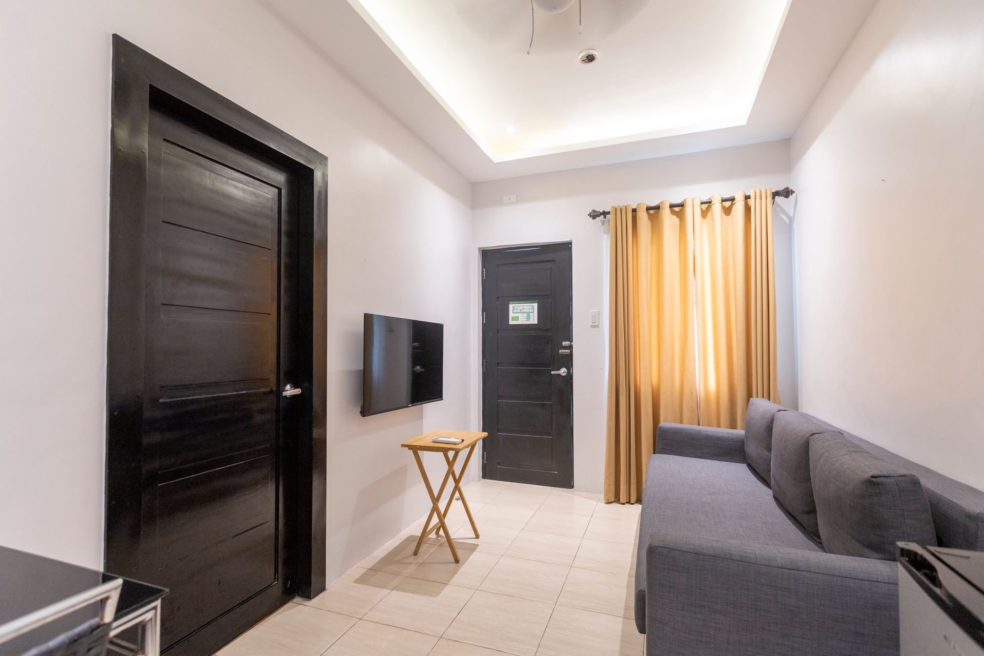 Small living area with a sofa, TV, small table, and two dark doors.