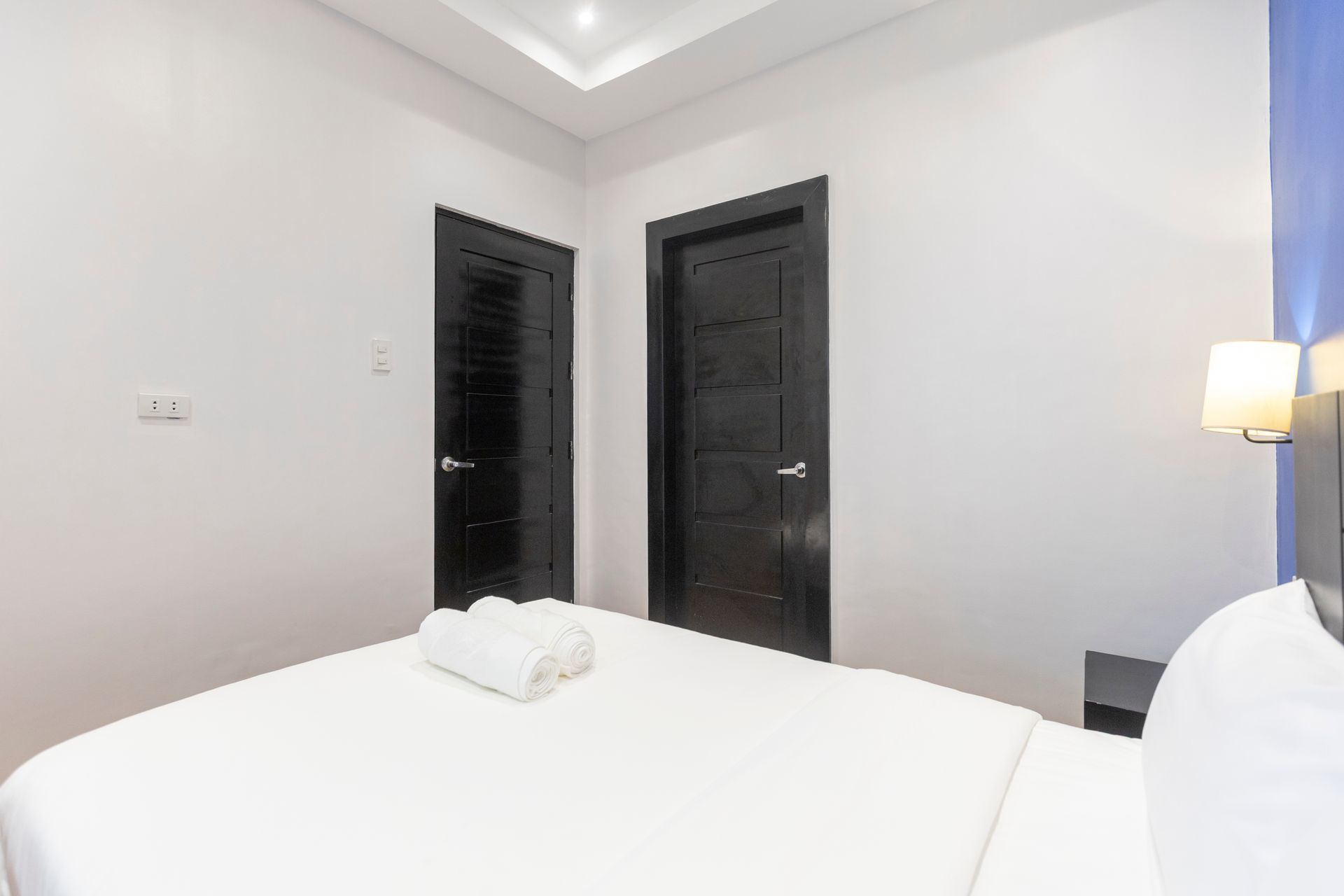 Bedroom interior with a bed, two dark doors, and white walls.