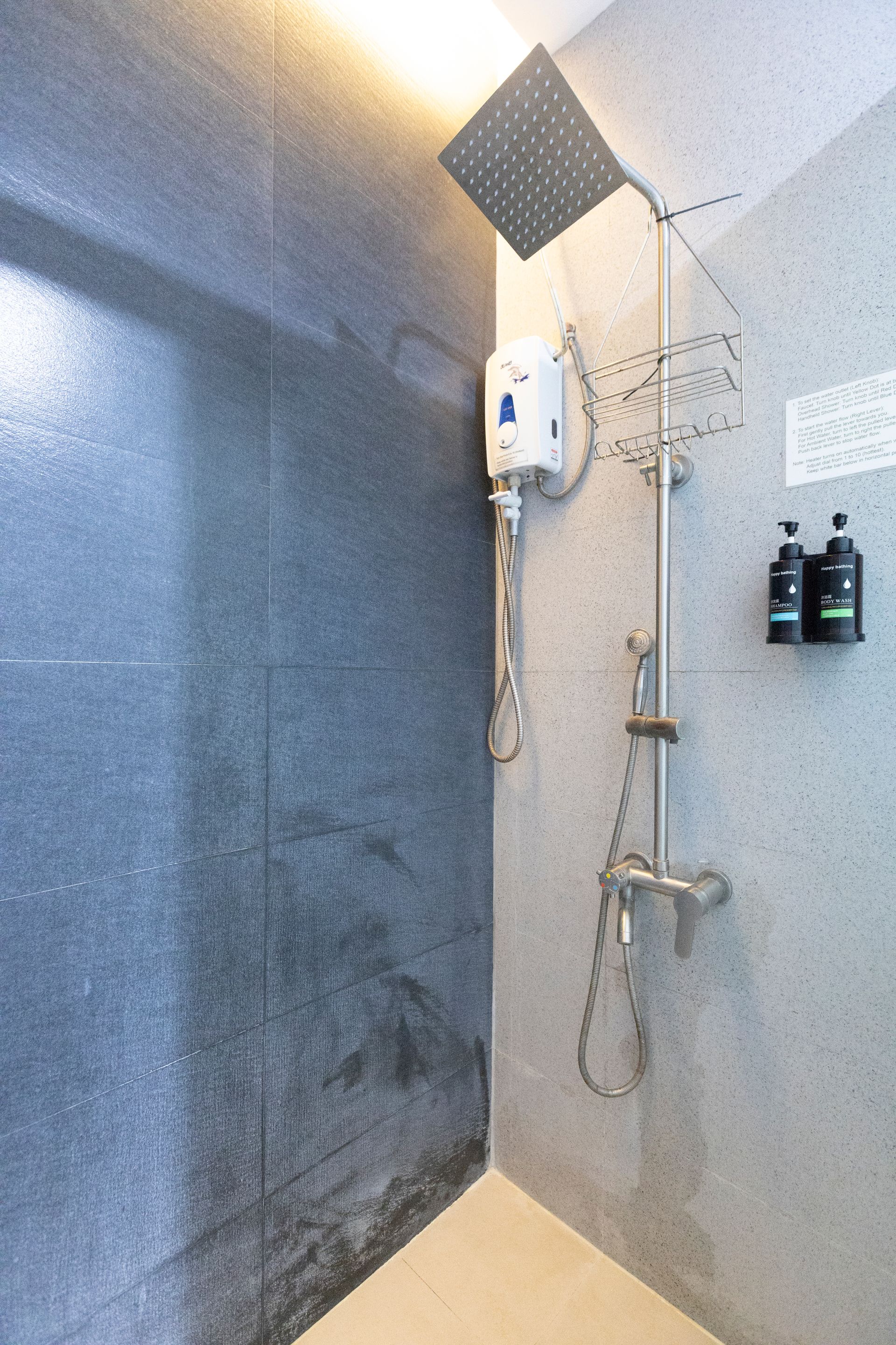 Shower with square showerhead and adjustable handheld sprayer against gray speckled walls.