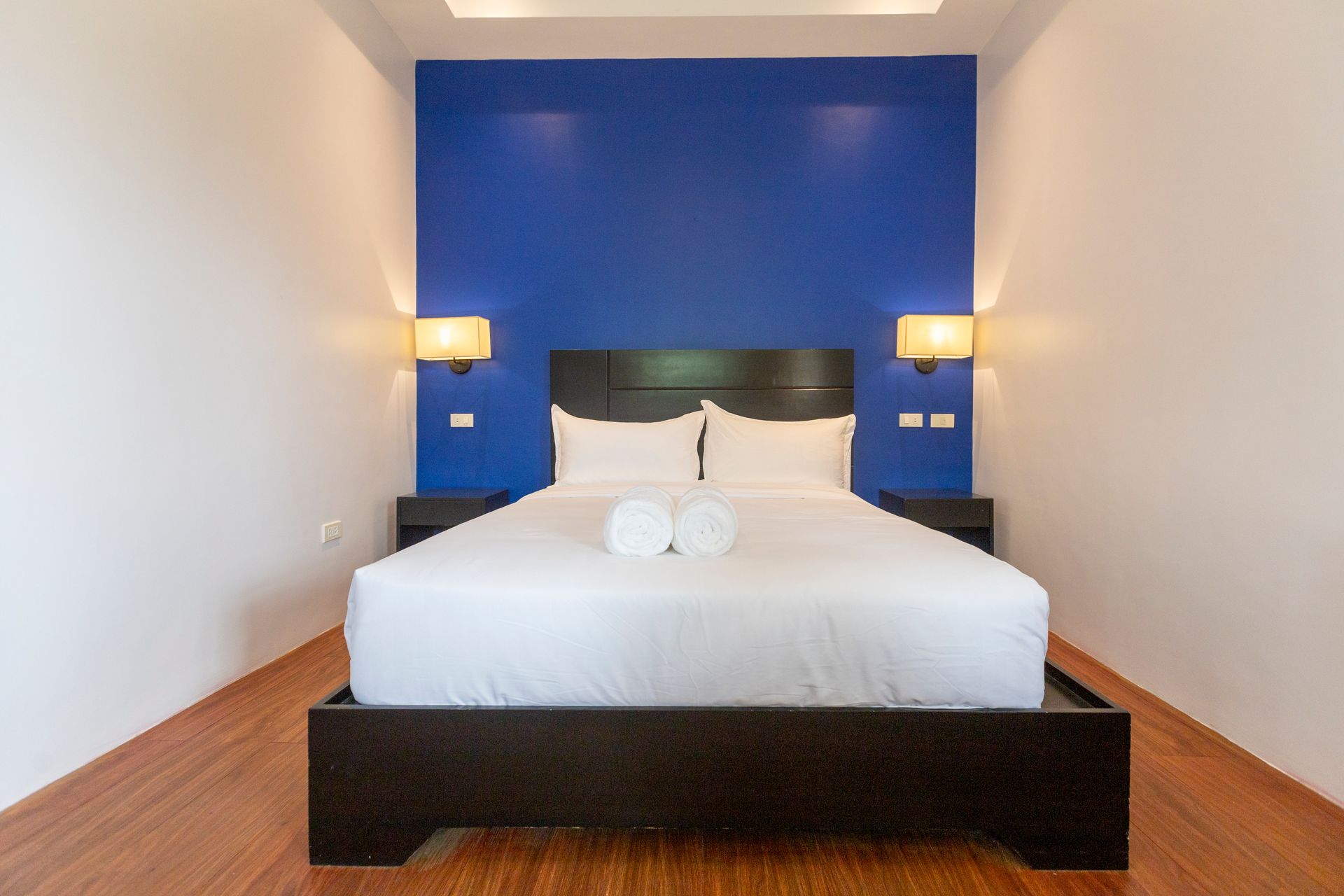 Bedroom with a white bed, blue accent wall, and sconce lighting.