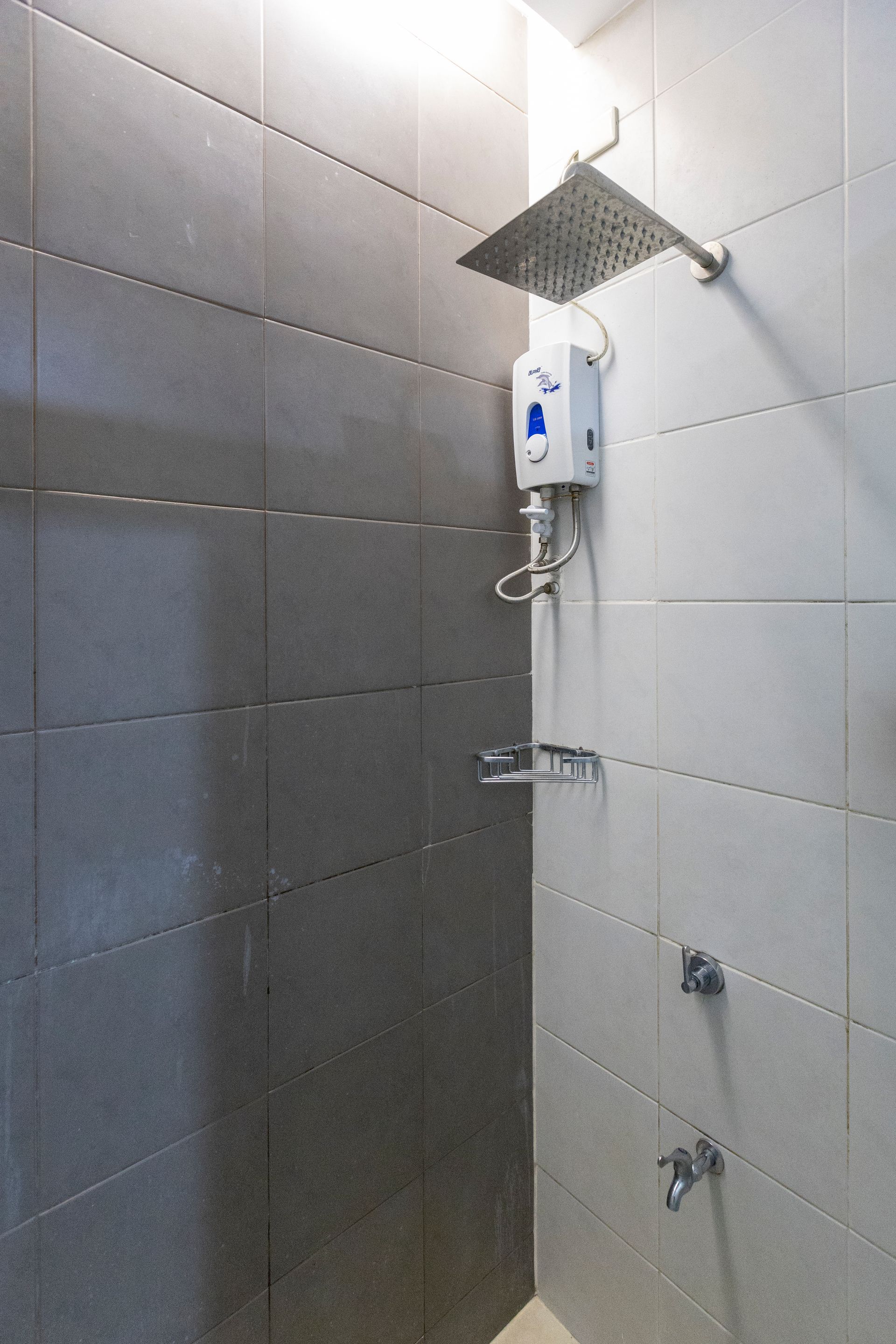 Shower stall with square rain shower head and electric water heater on tiled walls.