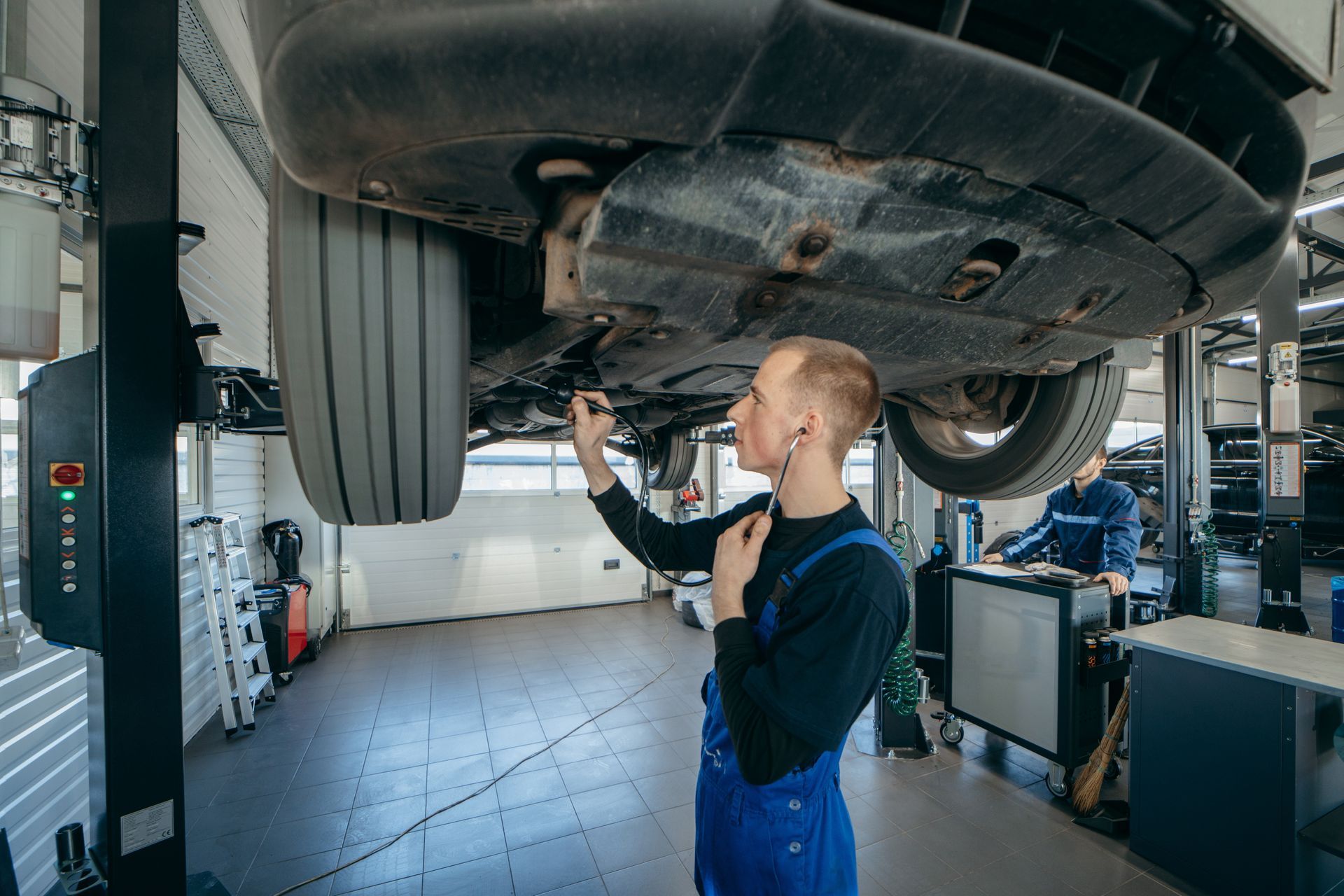 A man is working under a car in a garage | Ken's Tire and Auto