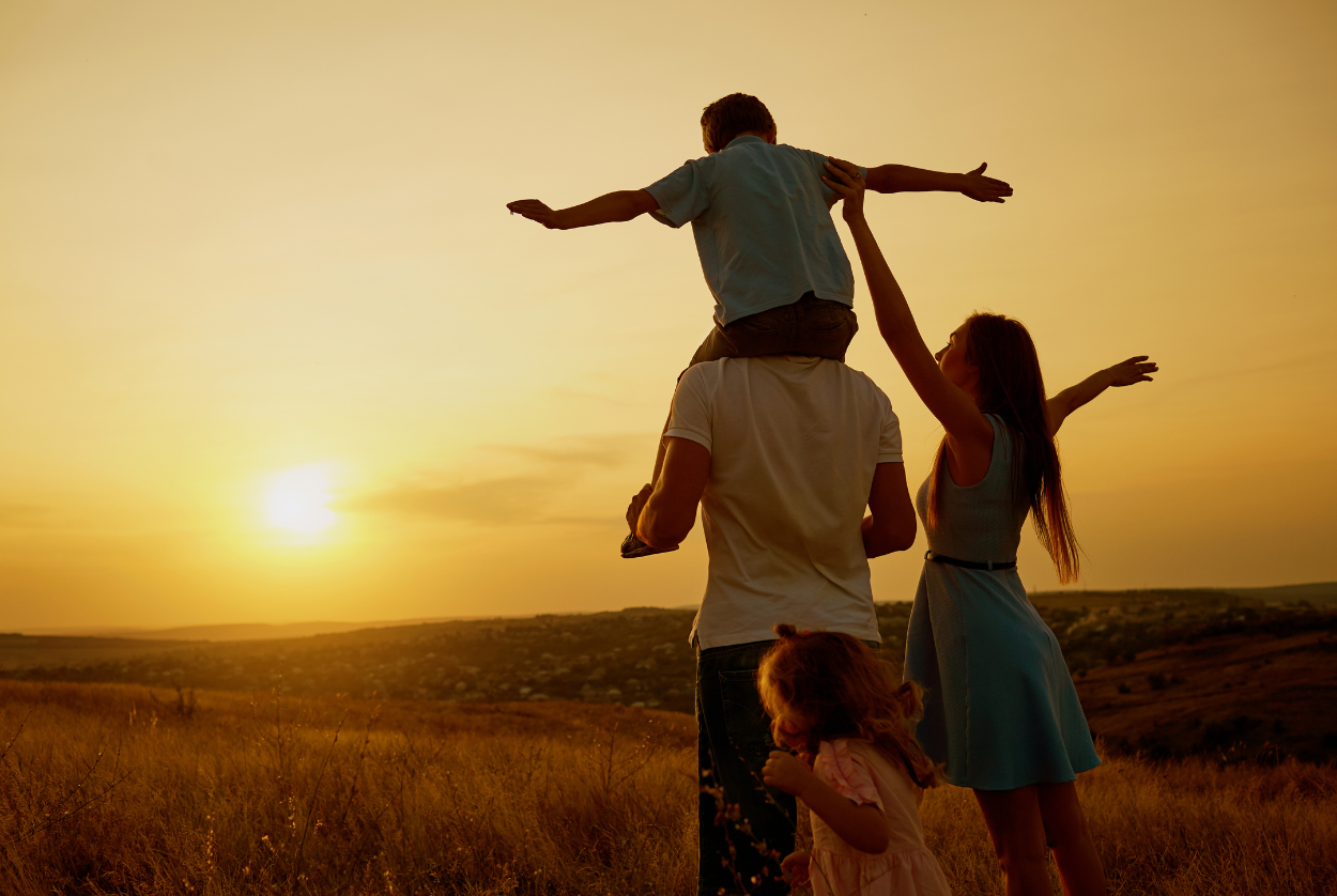 A family is standing in a field at sunset.