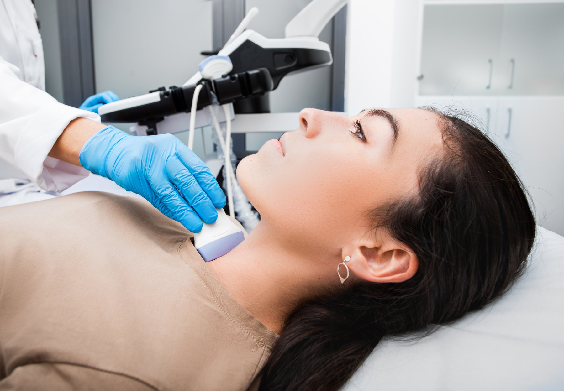 A woman is getting an ultrasound of her neck by a doctor.