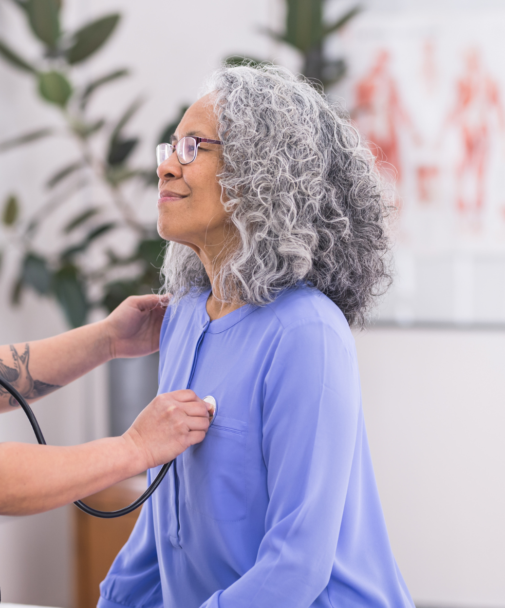 An older woman is being examined by a doctor with a stethoscope.