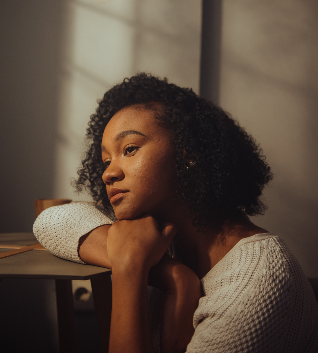 A woman is sitting at a table with her head resting on her arm.