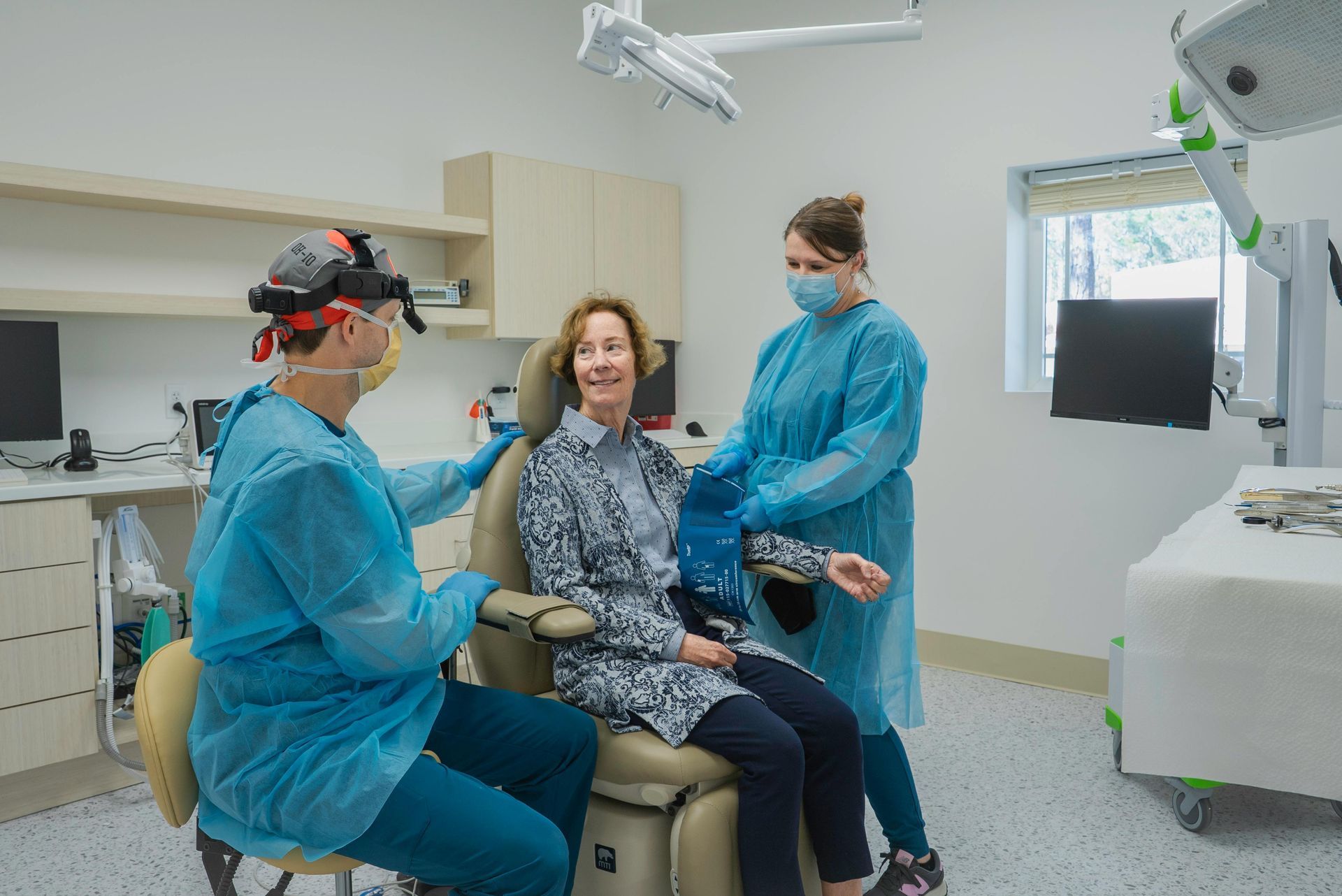 A woman is sitting in a dental chair being examined by two doctors.