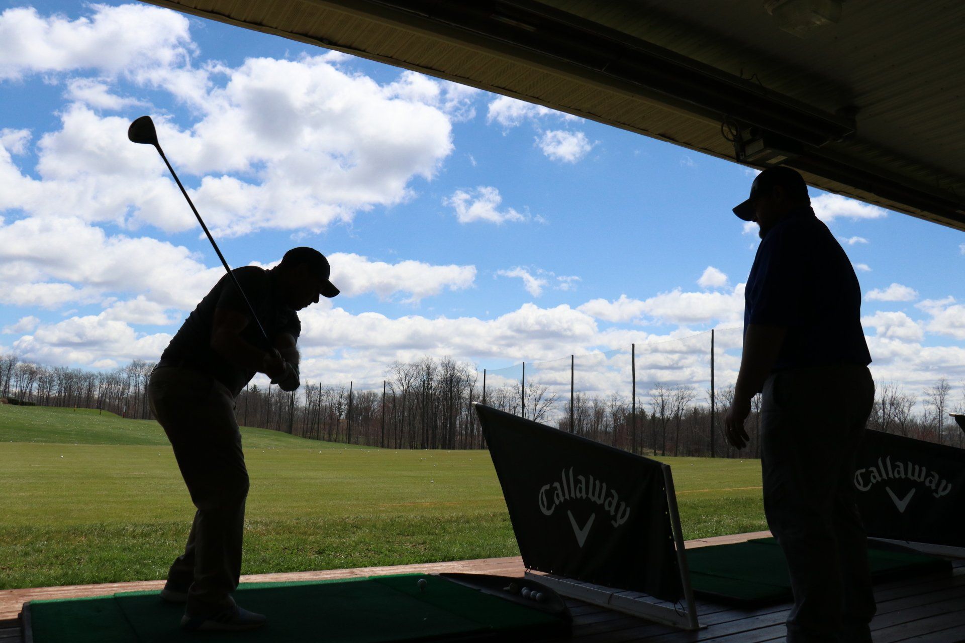 Silhouette of a man golfing on a driving range at a club fitting