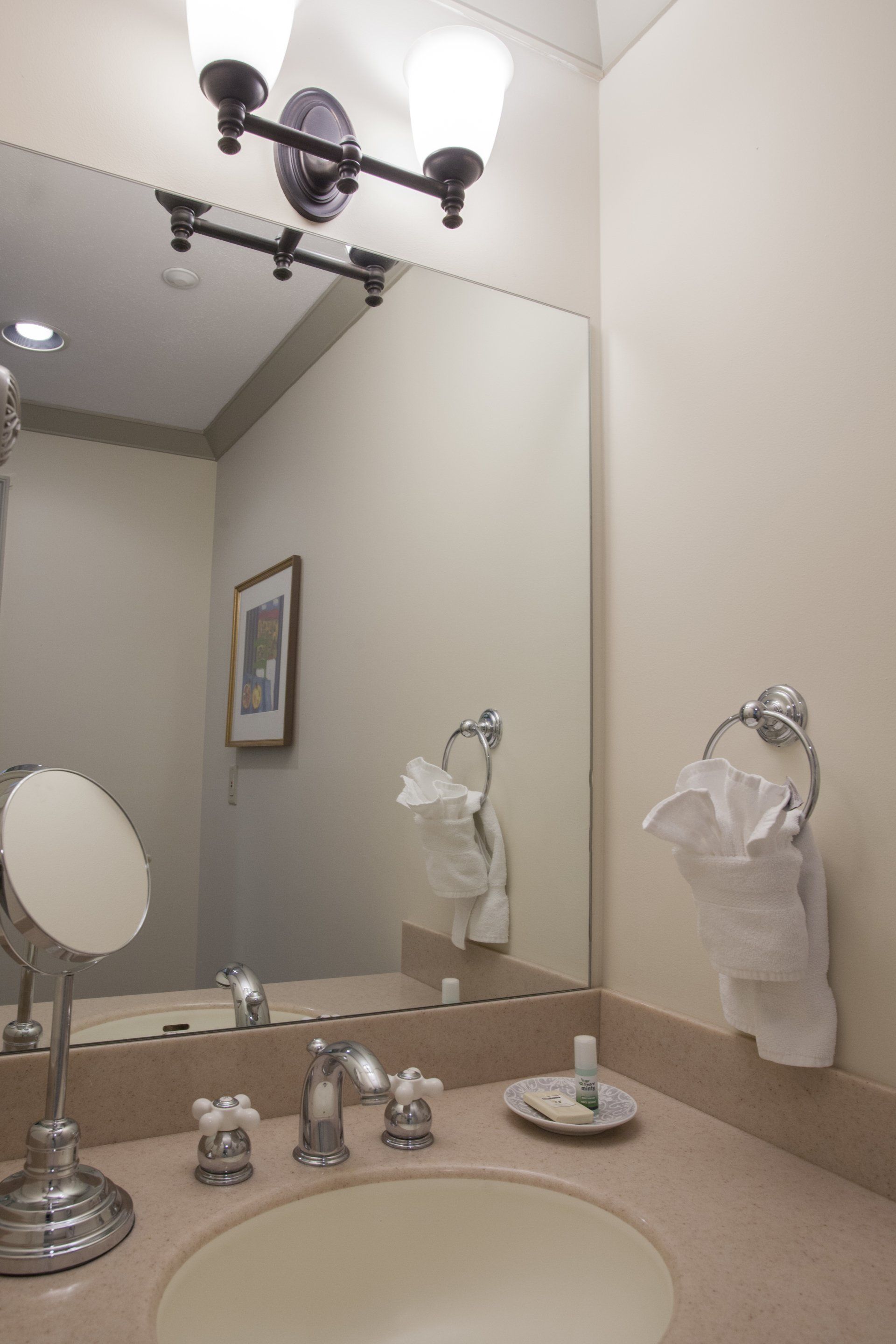 Bathroom counter with mirror, makeup mirror and a towel bar on the wall.