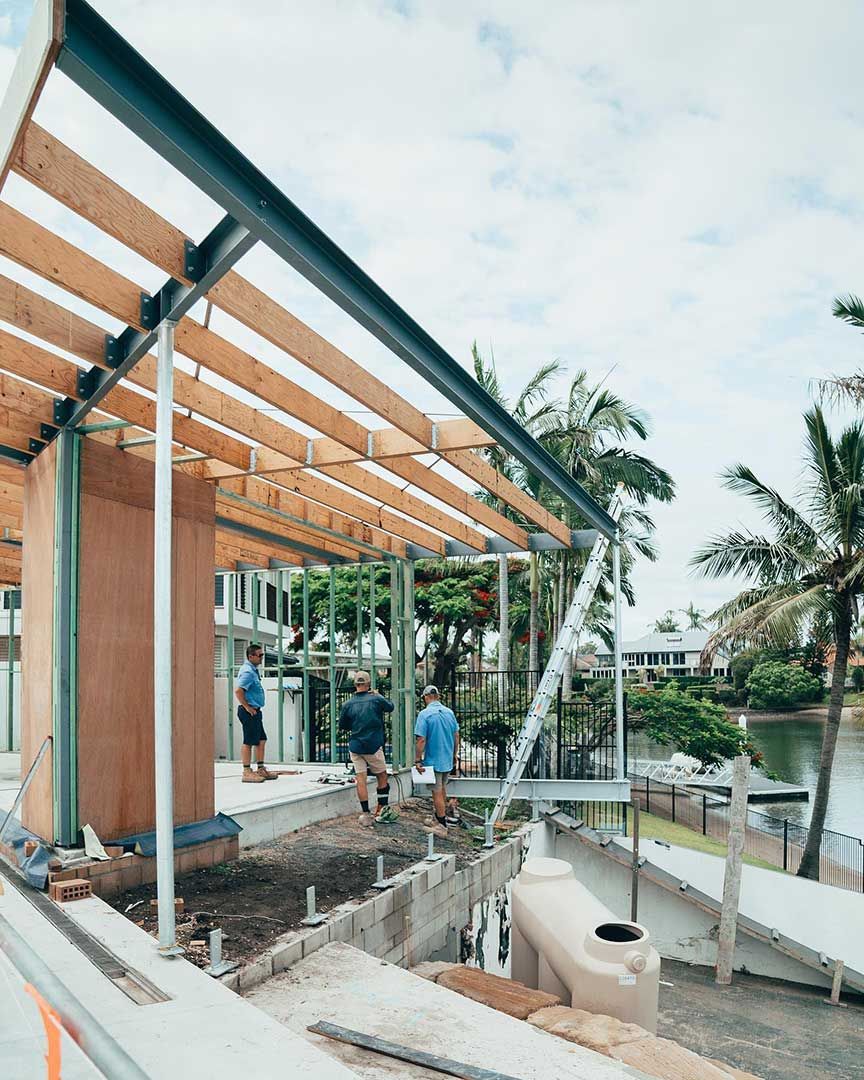 A Group of People Are Standing in Front of a Building Under Construction — JIC Projects Pty Ltd in Runaway Bay, QLD
