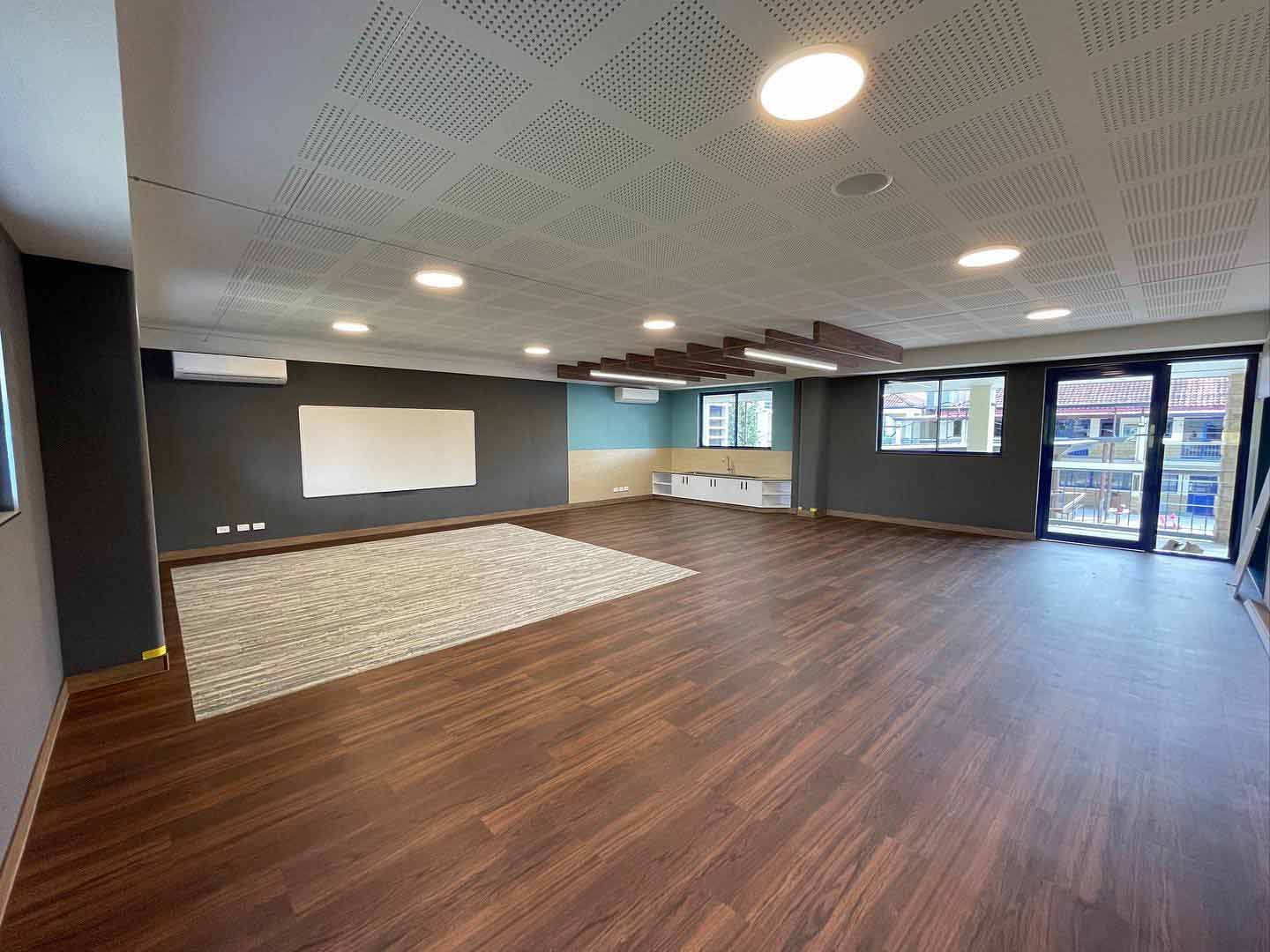 A Large Empty Room With Wooden Floors and a Whiteboard — JIC Projects Pty Ltd in Runaway Bay, QLD