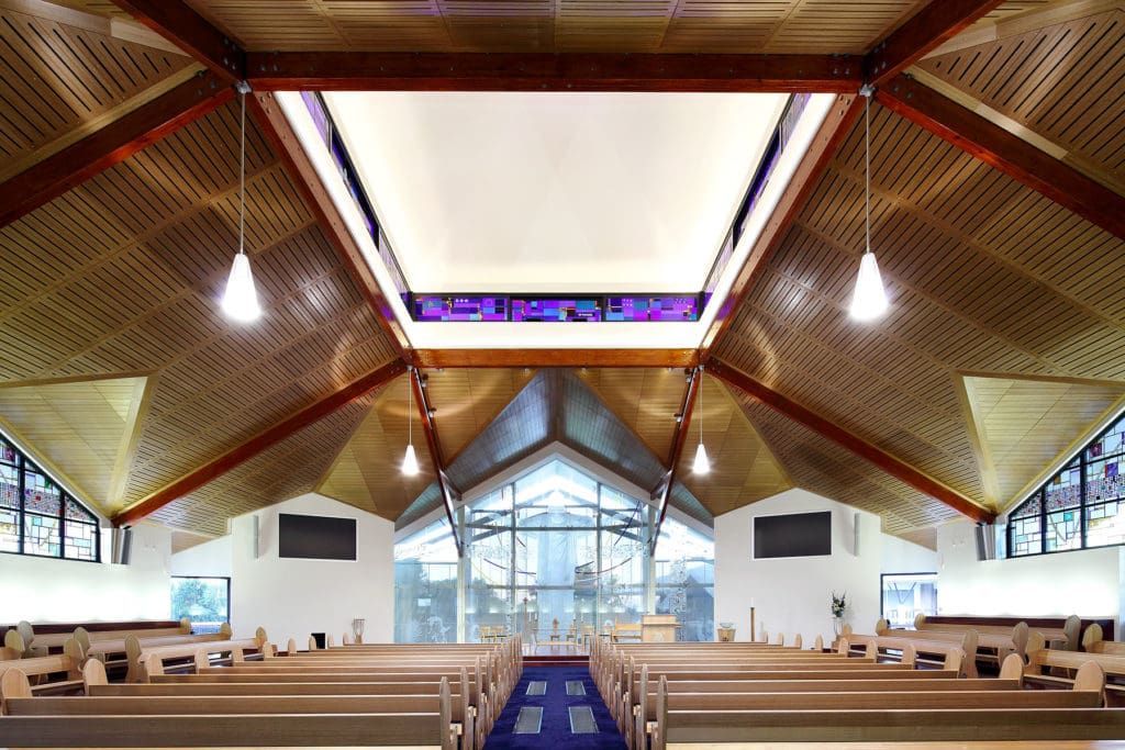 The Inside of a Church With Rows of Benches and a Stained Glass Window — JIC Projects Pty Ltd in Runaway Bay, QLD