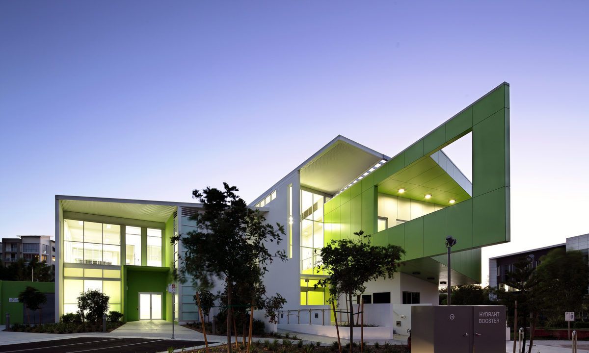 A green and white building with a blue sky in the background