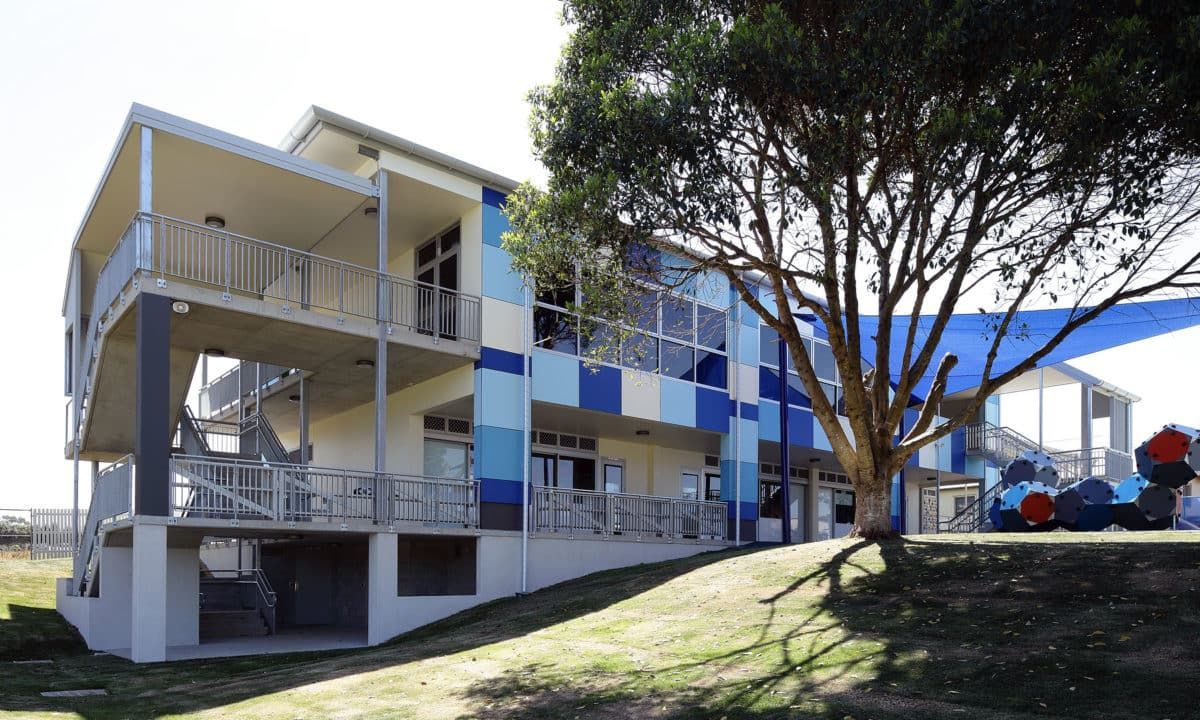 A green and white building with a blue sky in the background