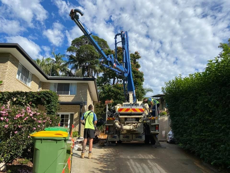 A Man is Standing Next to a Concrete Pump Truck in Front of a House — JIC Projects Pty Ltd in Runaway Bay, QLD