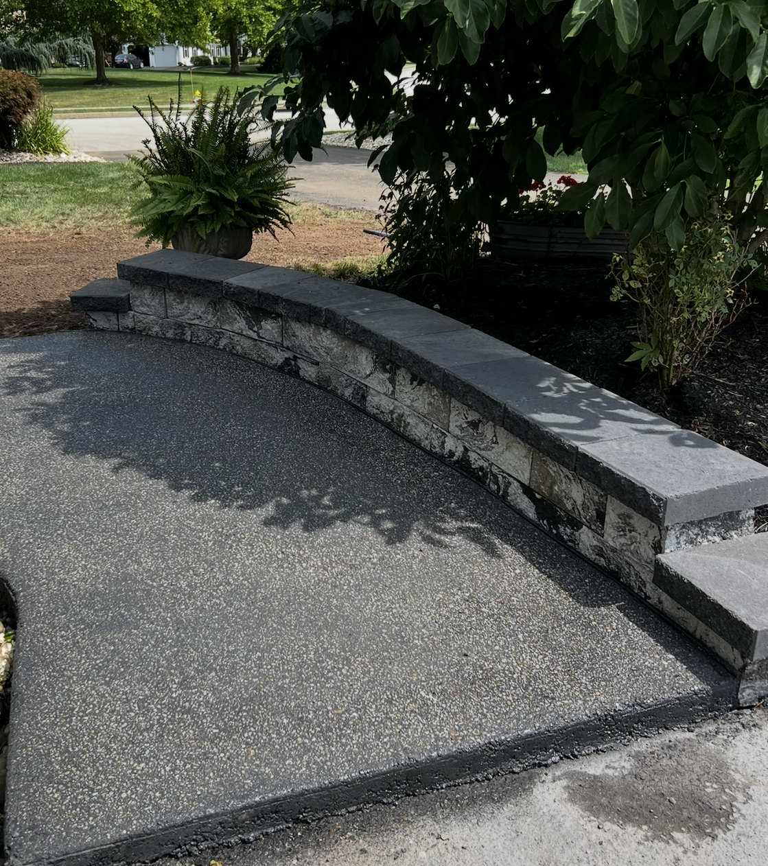 A concrete walkway with a stone wall in the background