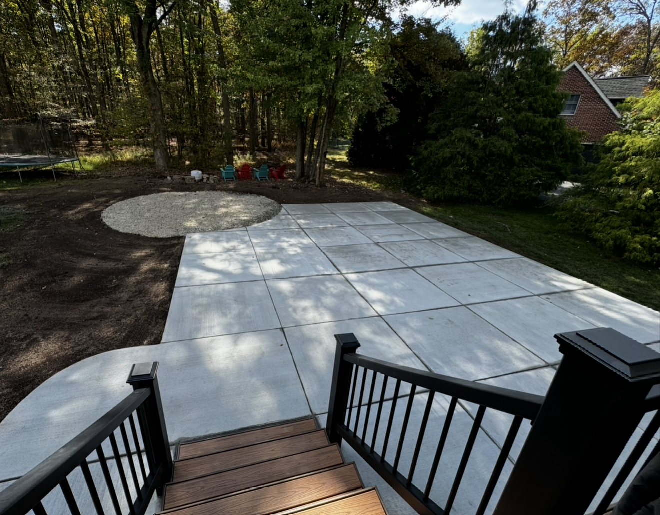 A concrete patio with stairs leading up to it and trees in the background.