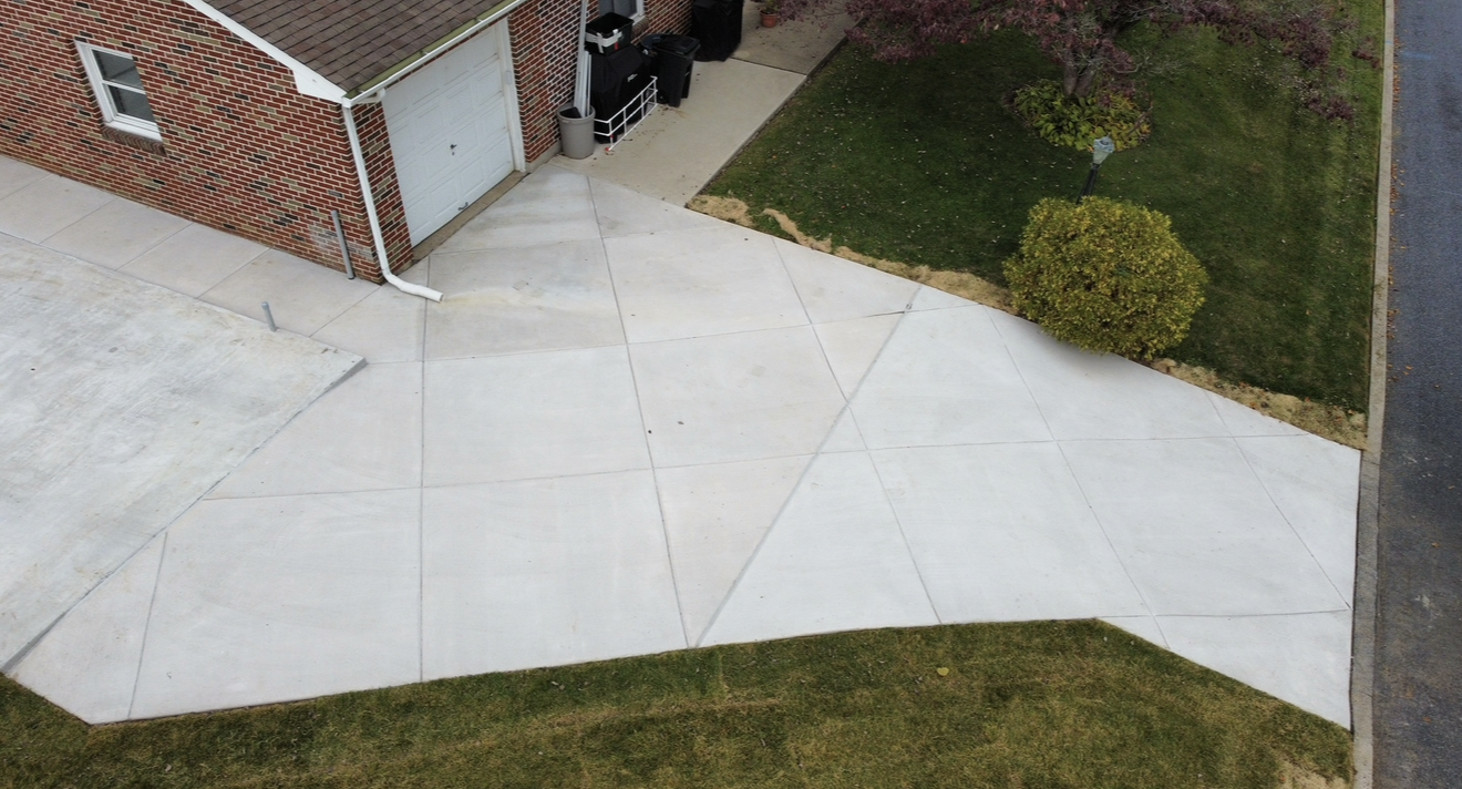 An aerial view of a concrete driveway leading to a brick house.