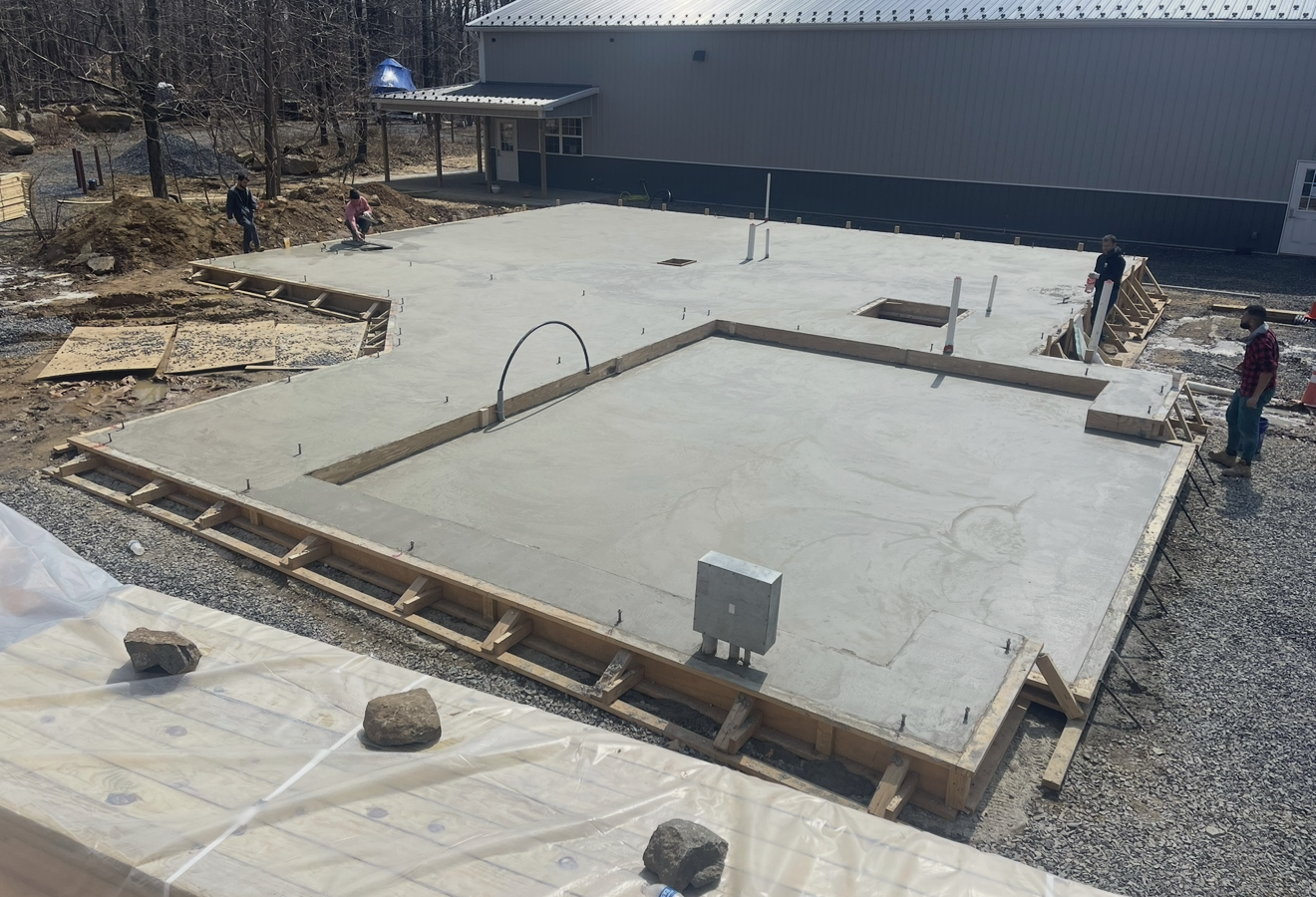 A concrete floor is being built in front of a building.