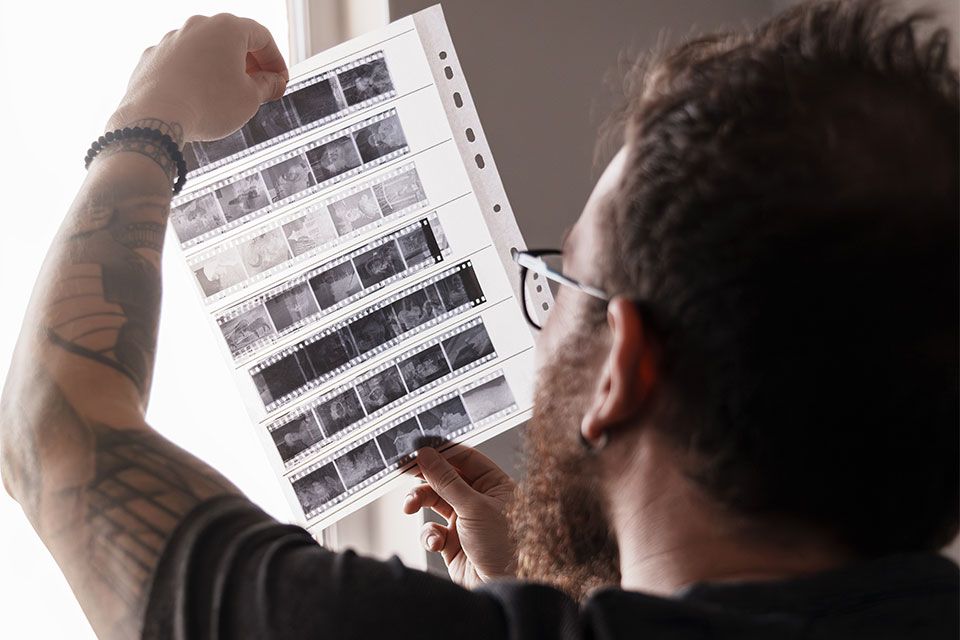 A person is holding a sheet of film negatives in their hand.