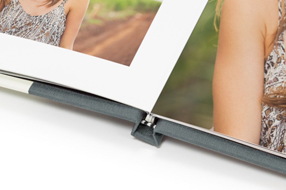 A photo book is open and flat on a white table with clear lay flat binding.