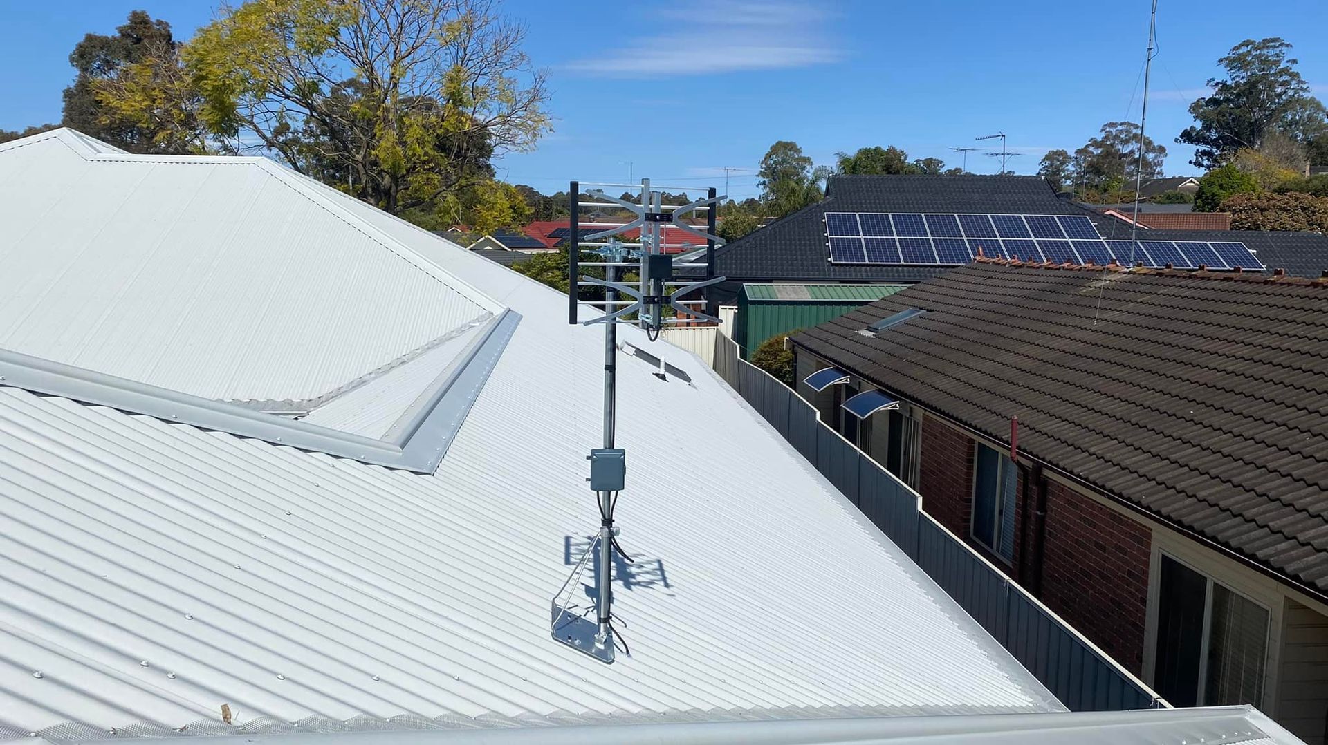 White Metal Roofs With Antenna and Solar Panels Under a Clear Blue Sky — Wide Area Communications in Hawkesbury, NSW